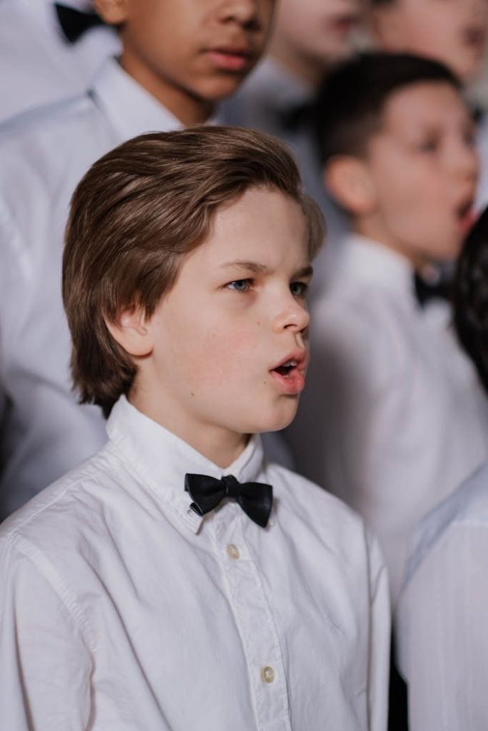 Portrait of young choir boys dressed in uniforms singing passionately in a performance.