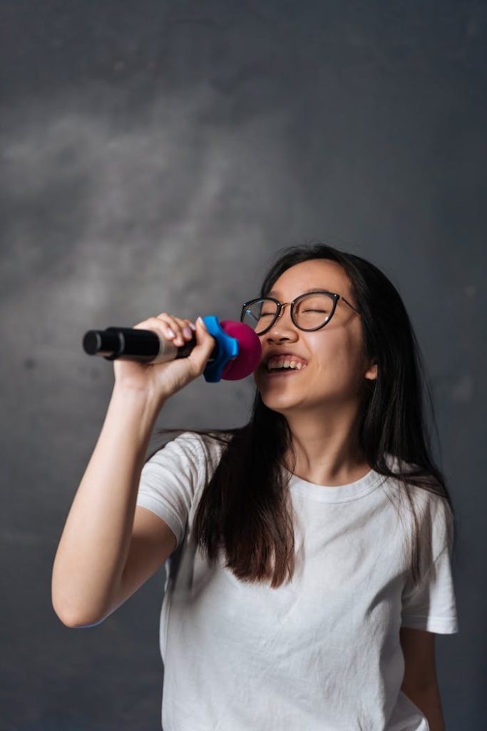 Young woman passionately singing into a microphone, enjoying the moment.